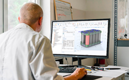 An instructor standing next to a laptop in front of a window.